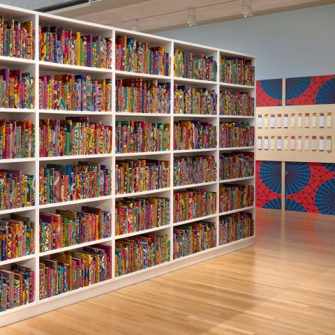 A gallery filled with book shelves of colorful books with names written on them.